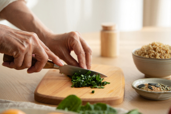 close up of persons hands chopping greens with a knife