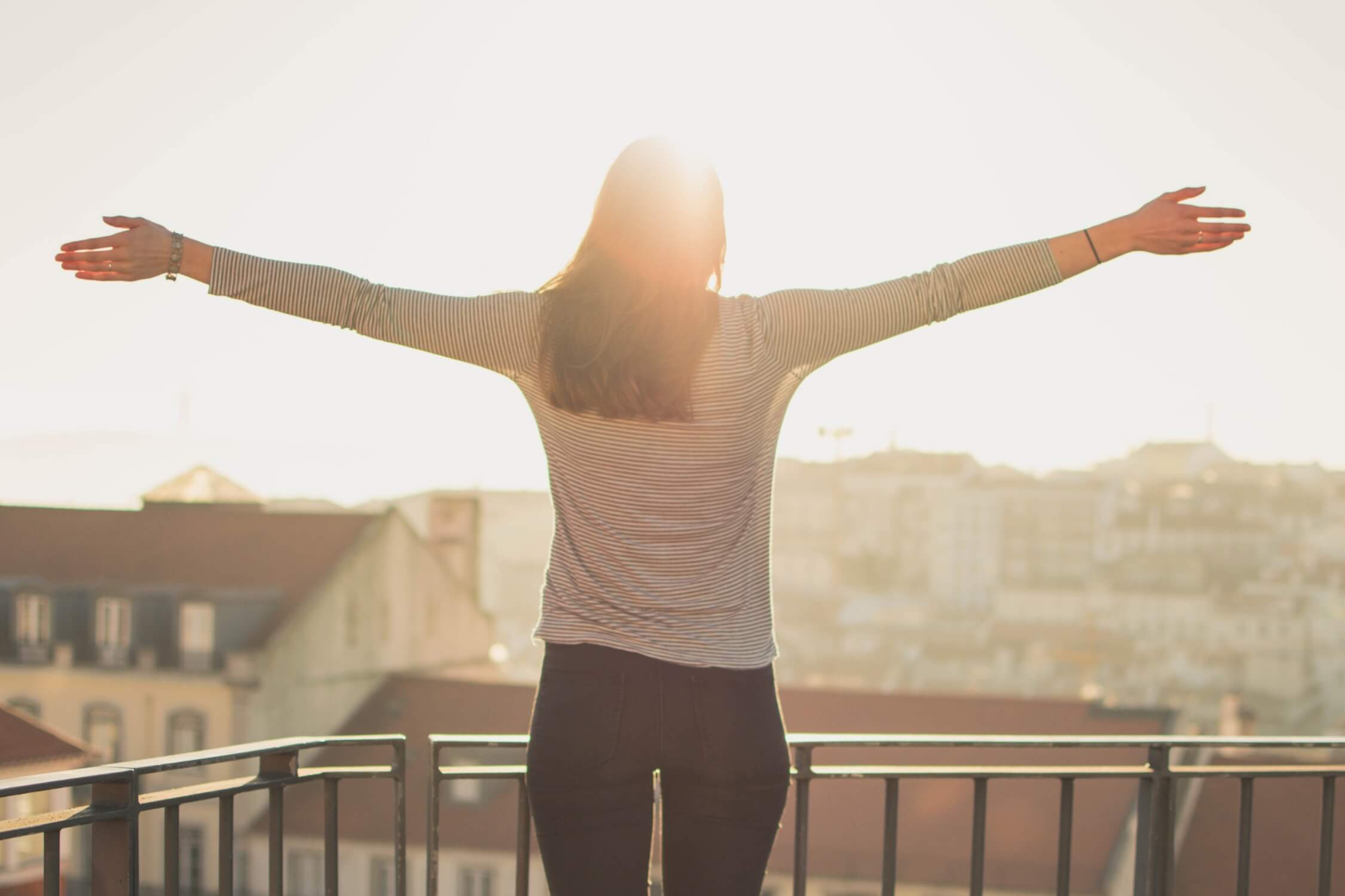 woman with outstretched arms facing the sun