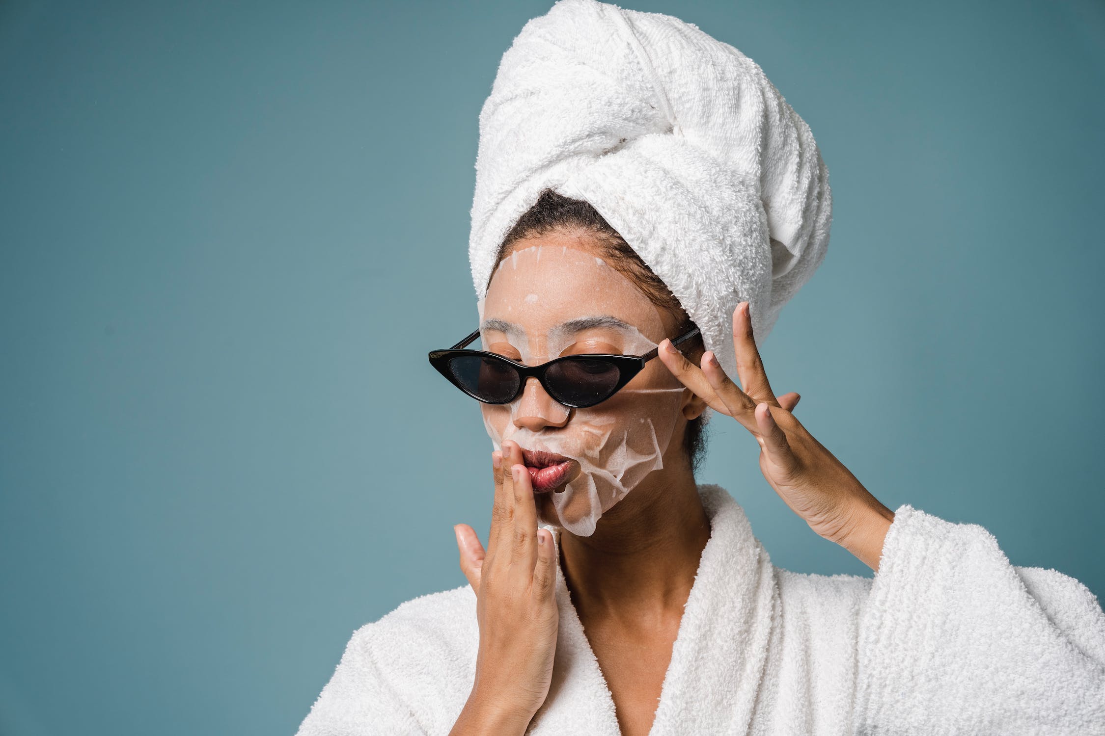 woman with a sheet face mask and sunglasses on