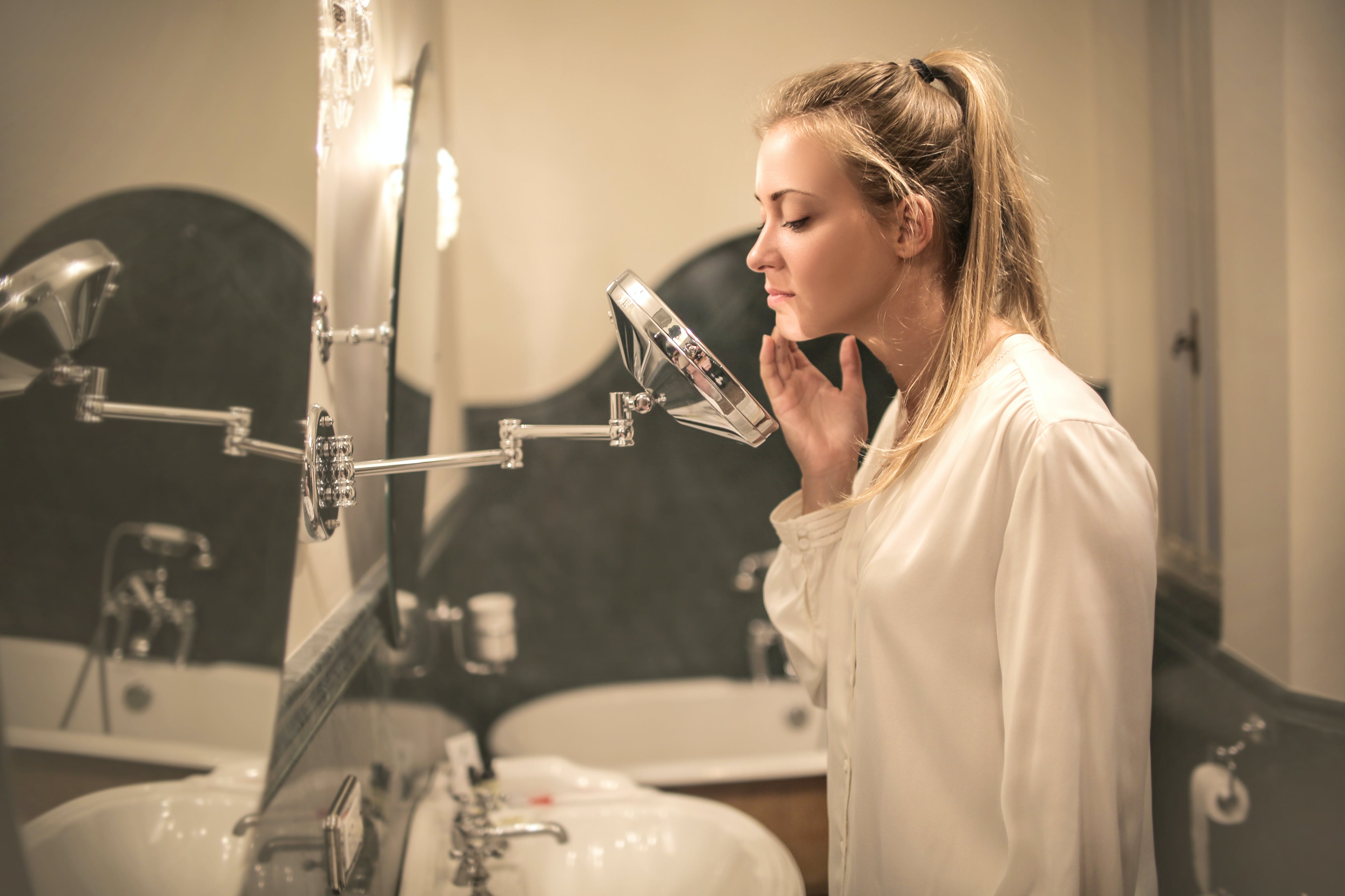 woman inspecting her acne prone skin in the mirror